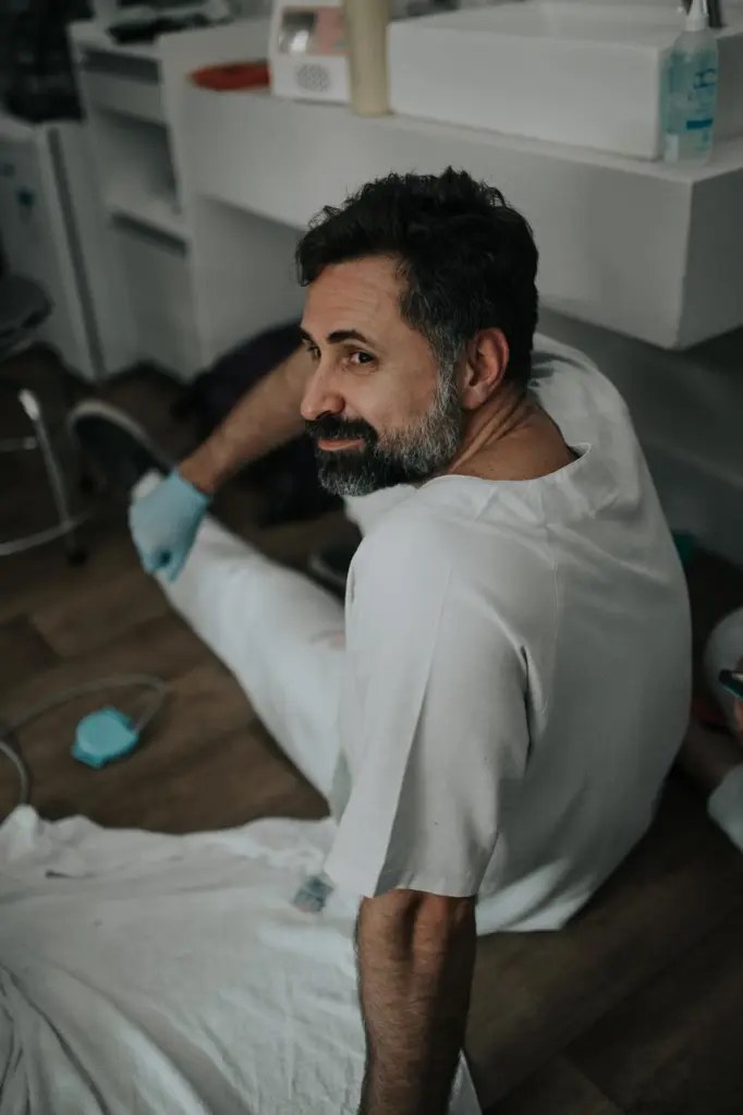 Dr. Pedro Melo em sala de parto, no chão, ao lado da parturiente